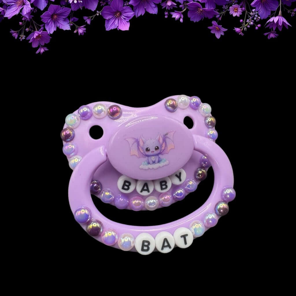 Purple bat-themed adult pacifier with text beads spelling 'Baby Bat,' surrounded by various shades of purple pearls for a cute and gothic aesthetic.
