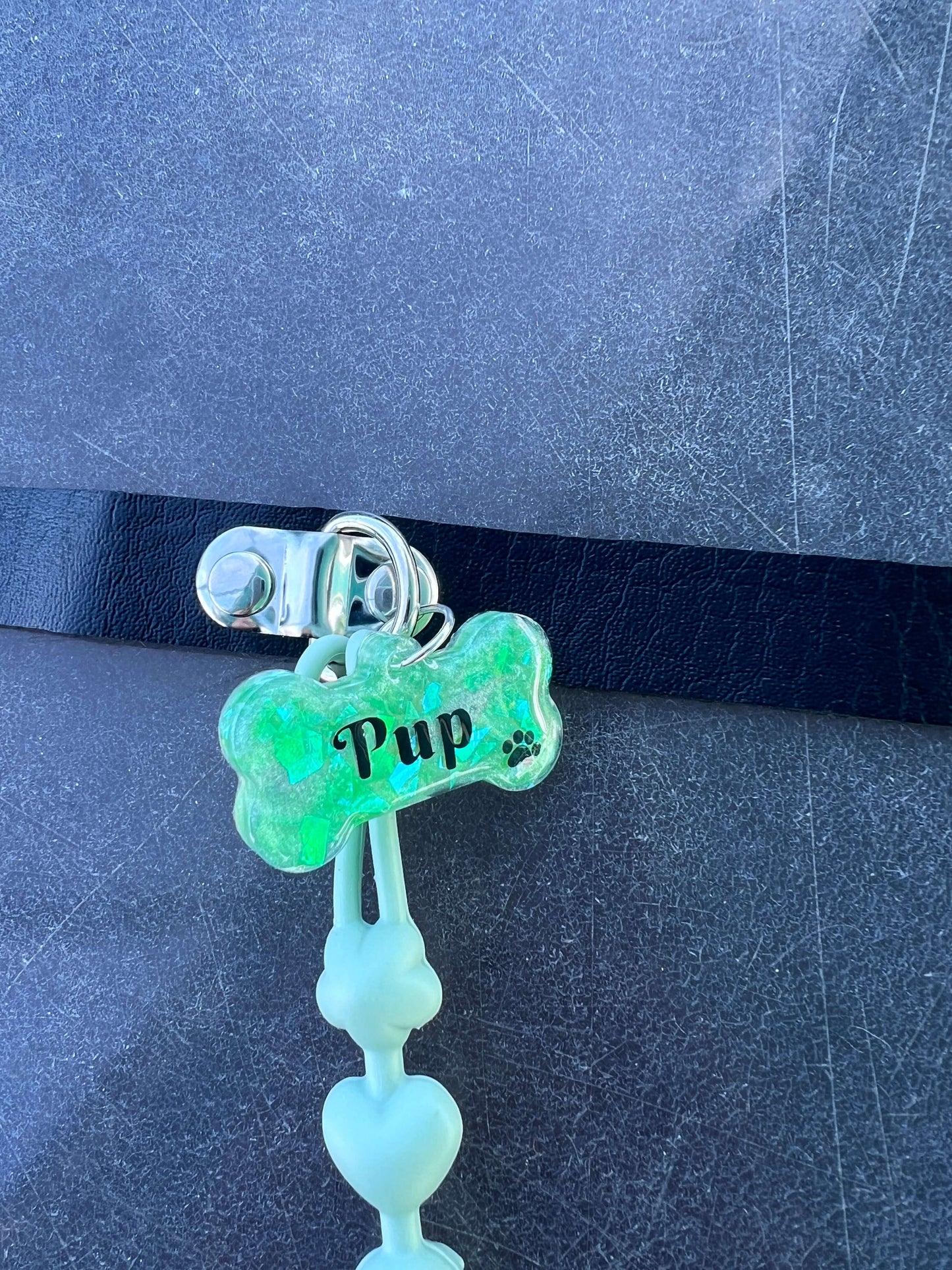 Adult pacifier choker featuring a comfortable choker with an attached adult pacifier, connected by a chewable silicone string. A customizable resin name tag is displayed at the center for personalization.