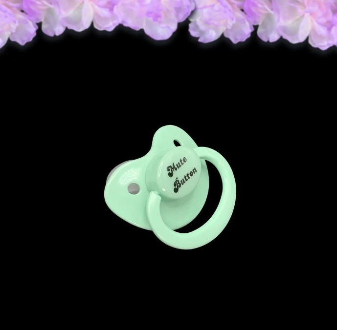 A mint adult pacifier with elegant black text in the center that reads "Mute Button," featuring a soft and playful design.