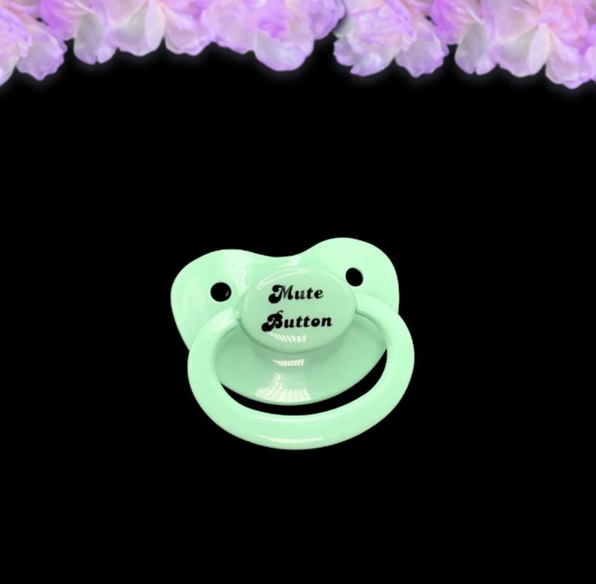 A mint adult pacifier with elegant black text in the center that reads "Mute Button," featuring a soft and playful design.
