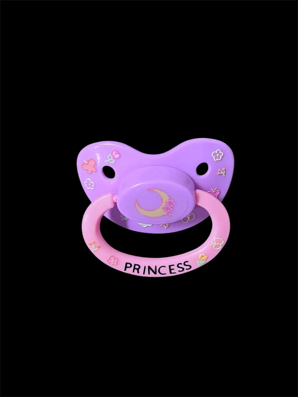 Adult deco pacifier featuring glow-in-the-dark flowers and butterflies on the shield, a moon centerpiece, and the word 'Princess' on the handle for a magical and elegant design.