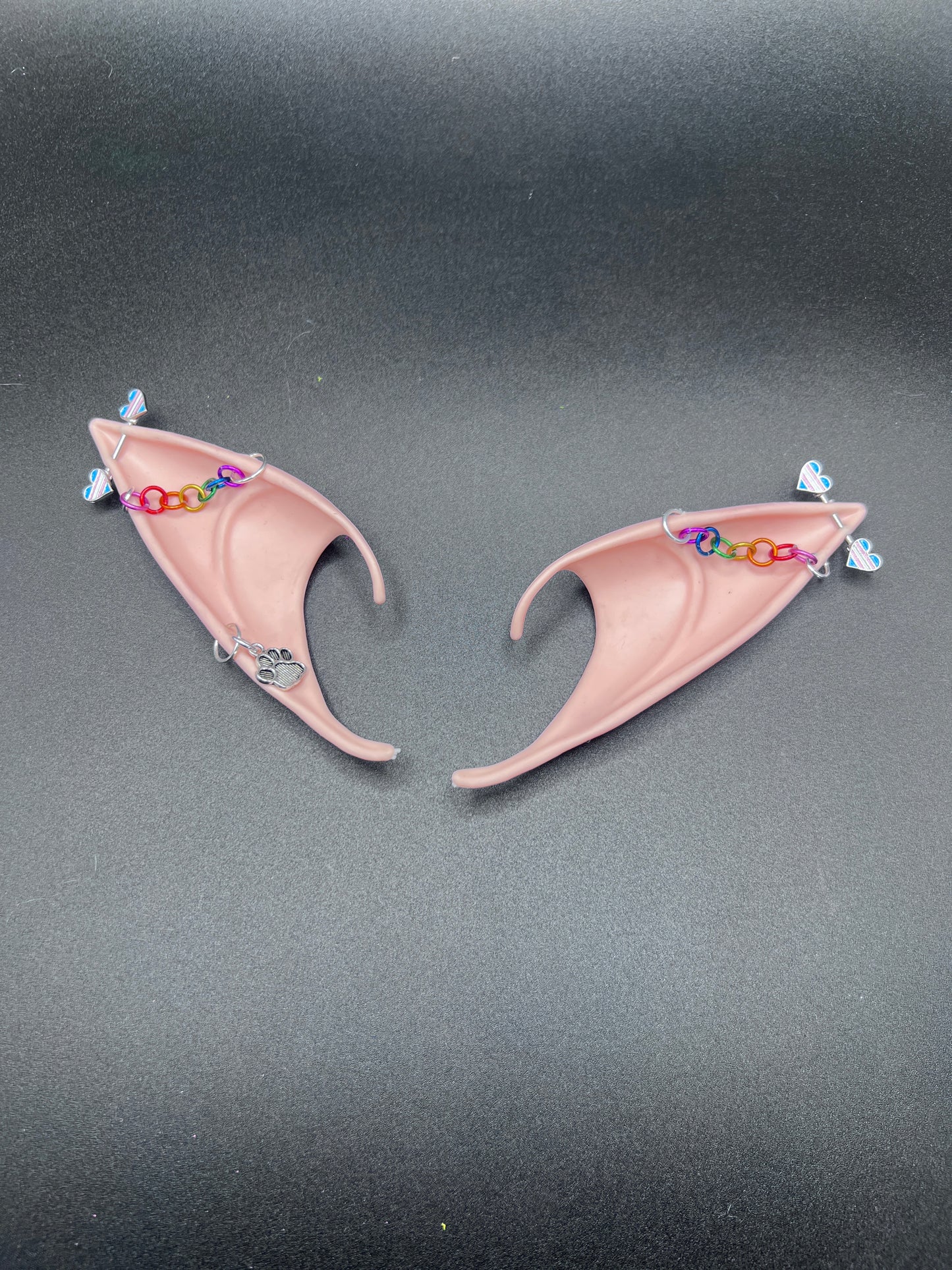 Pair of pink fairy elf ears with colorful chain on a dark background
