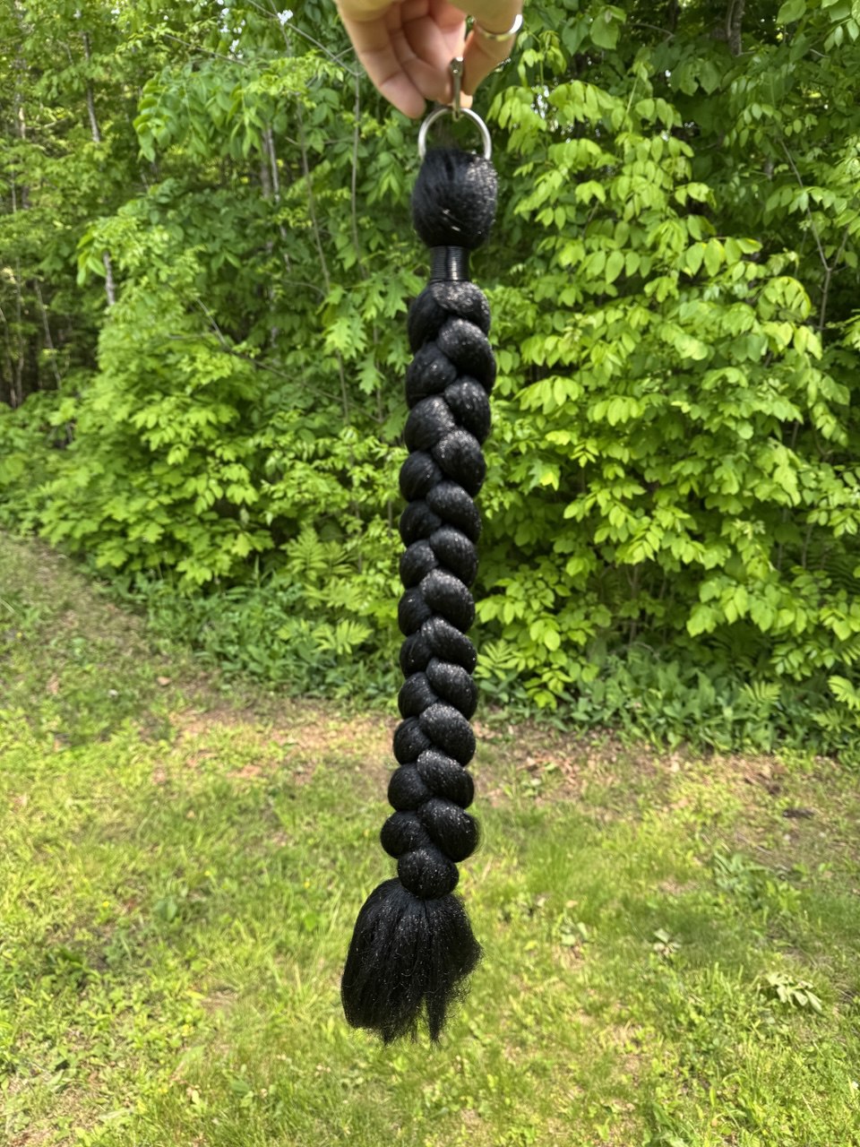 black horse tail that is 25 inches showing black wire wrapping and O ring attachment