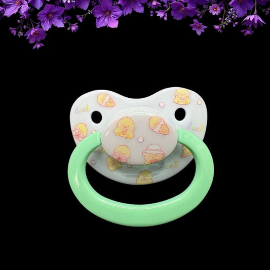 ABDL pacifier featuring a cute yellow duck design on the shield and button, adding a playful and adorable touch.