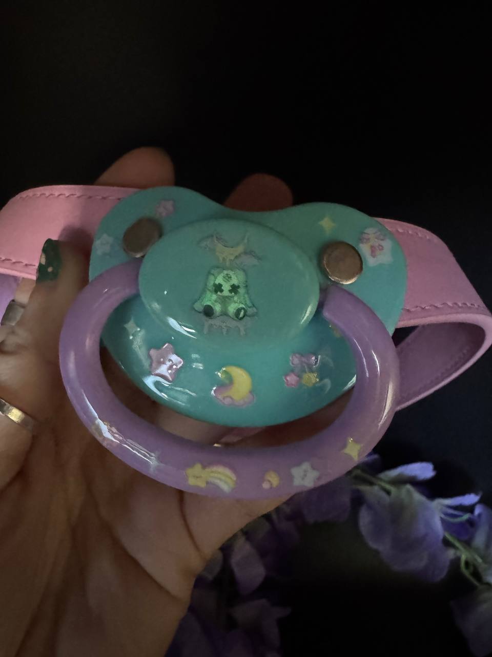 adult pacifier with pink straps in the dark showing glowing design