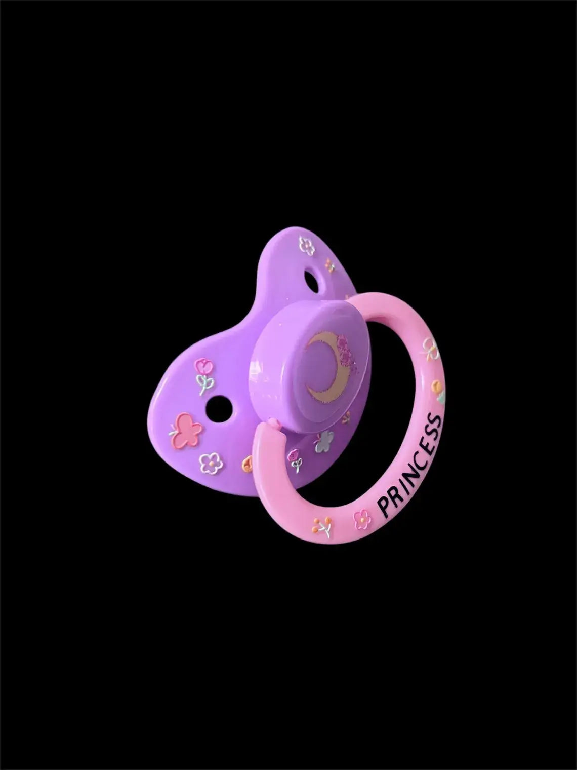 Adult deco pacifier featuring glow-in-the-dark flowers and butterflies on the shield, a moon centerpiece, and the word 'Princess' on the handle for a magical and elegant design.