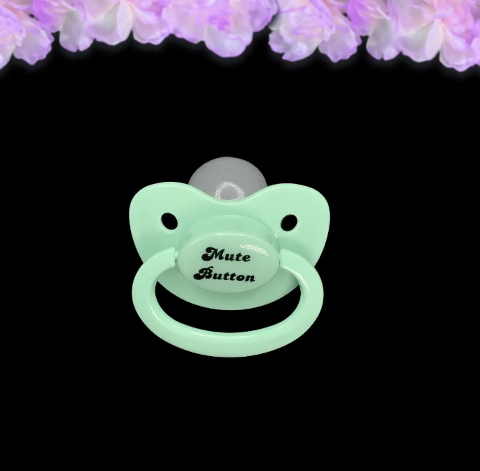 A mint adult pacifier with elegant black text in the center that reads "Mute Button," featuring a soft and playful design.