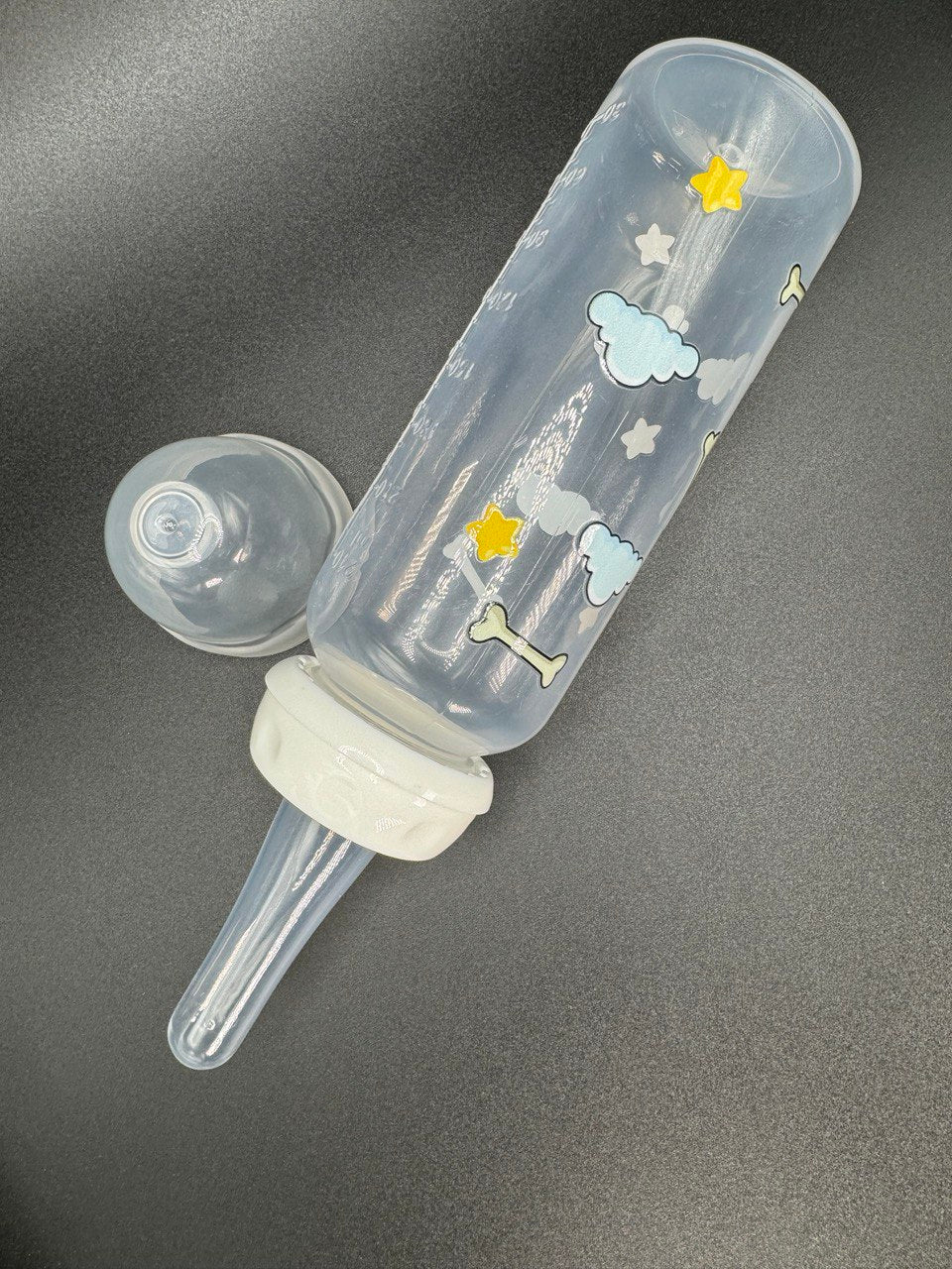 Nighttime dog-themed adult baby bottle featuring a wrap-around design of dog bones, fluffy clouds, and twinkling stars, creating a cozy and comforting aesthetic.