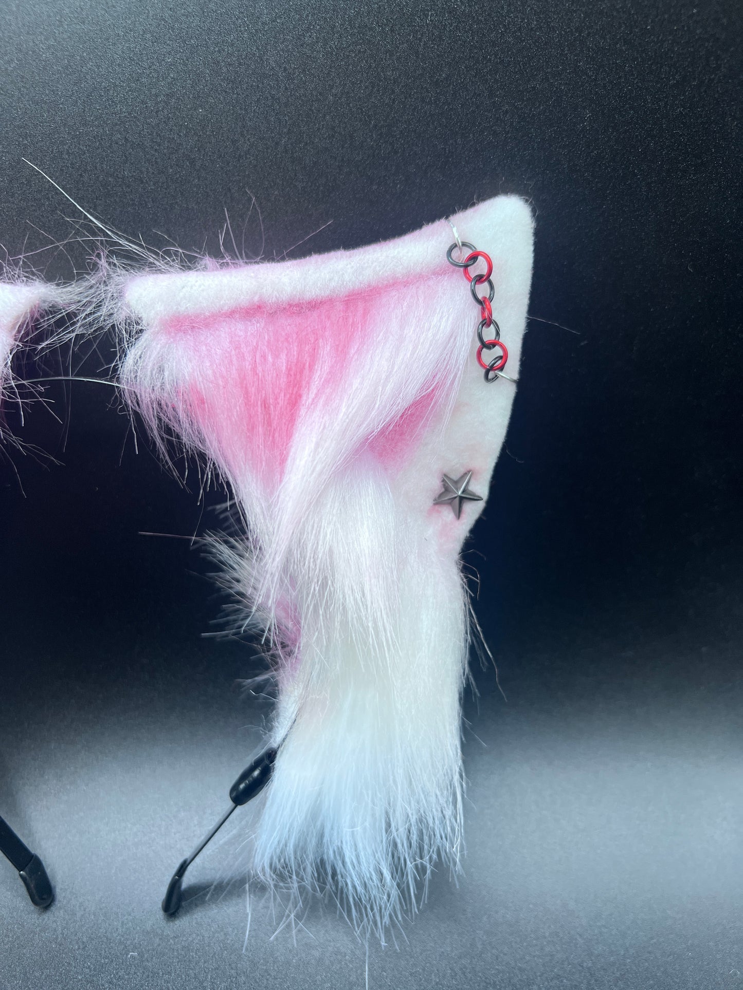 White and red cat ear with chain piercing on a dark background