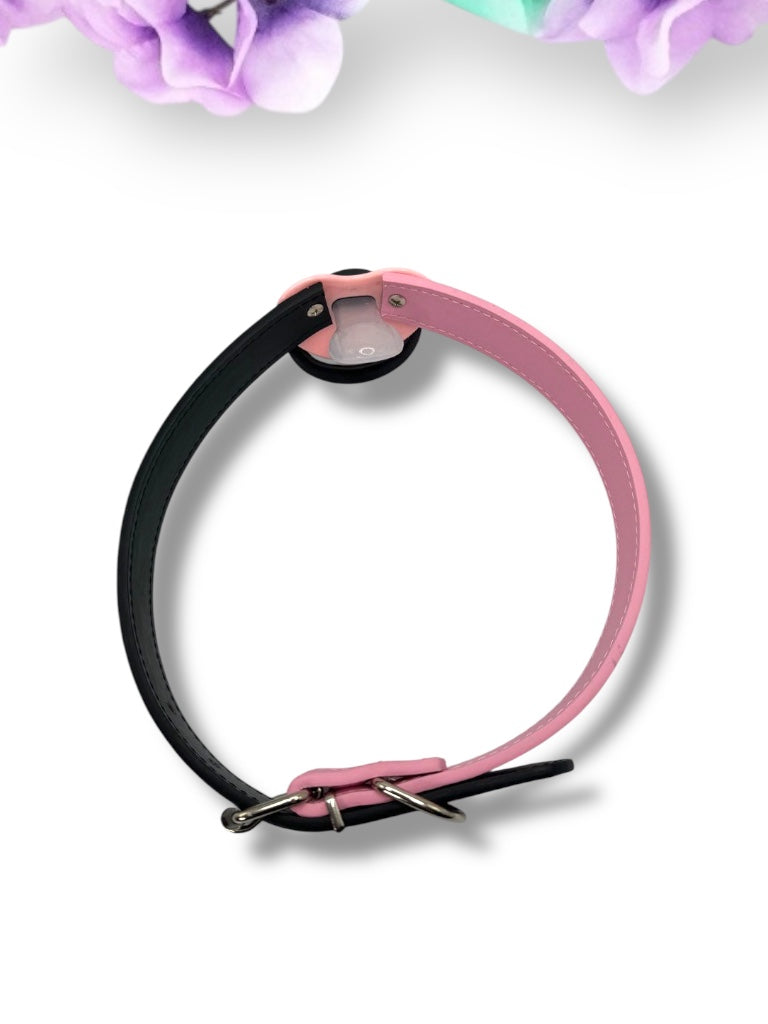 Adult pacifier gag featuring a black and pink pacifier with a punk bear design on the center button, the word 'Brat' in pink on the handle, and mismatched straps—one black and one pink—for a bold, edgy look.