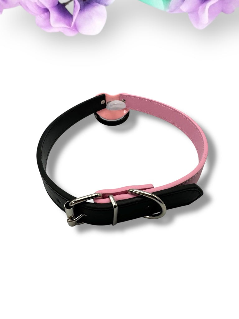 Adult pacifier gag featuring a black and pink pacifier with a punk bear design on the center button, the word 'Brat' in pink on the handle, and mismatched straps—one black and one pink—for a bold, edgy look.