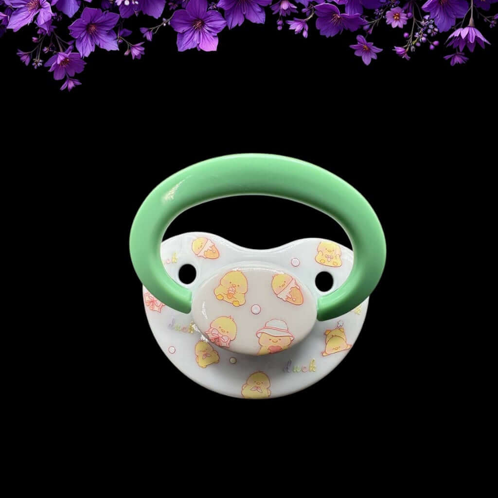 ABDL pacifier featuring a cute yellow duck design on the shield and button, adding a playful and adorable touch.