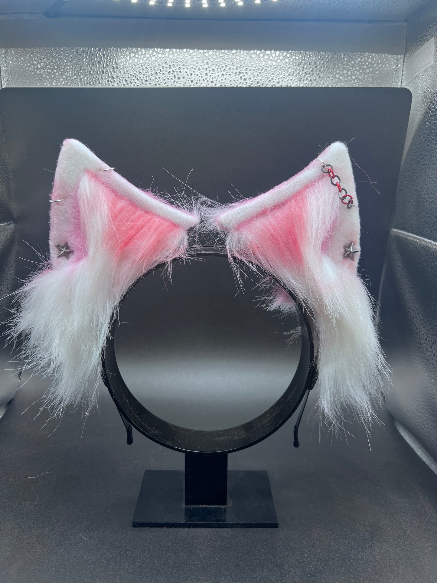 Cat ears with pink interior on a stand against a dark background