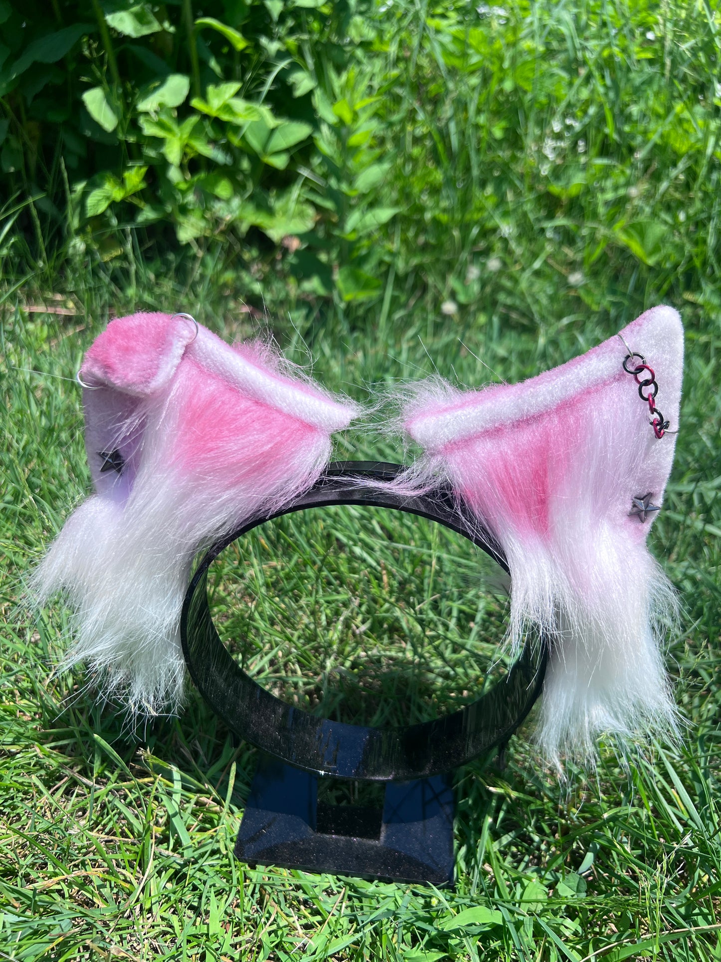 red and white furry ear headband with bent ear on a grassy background