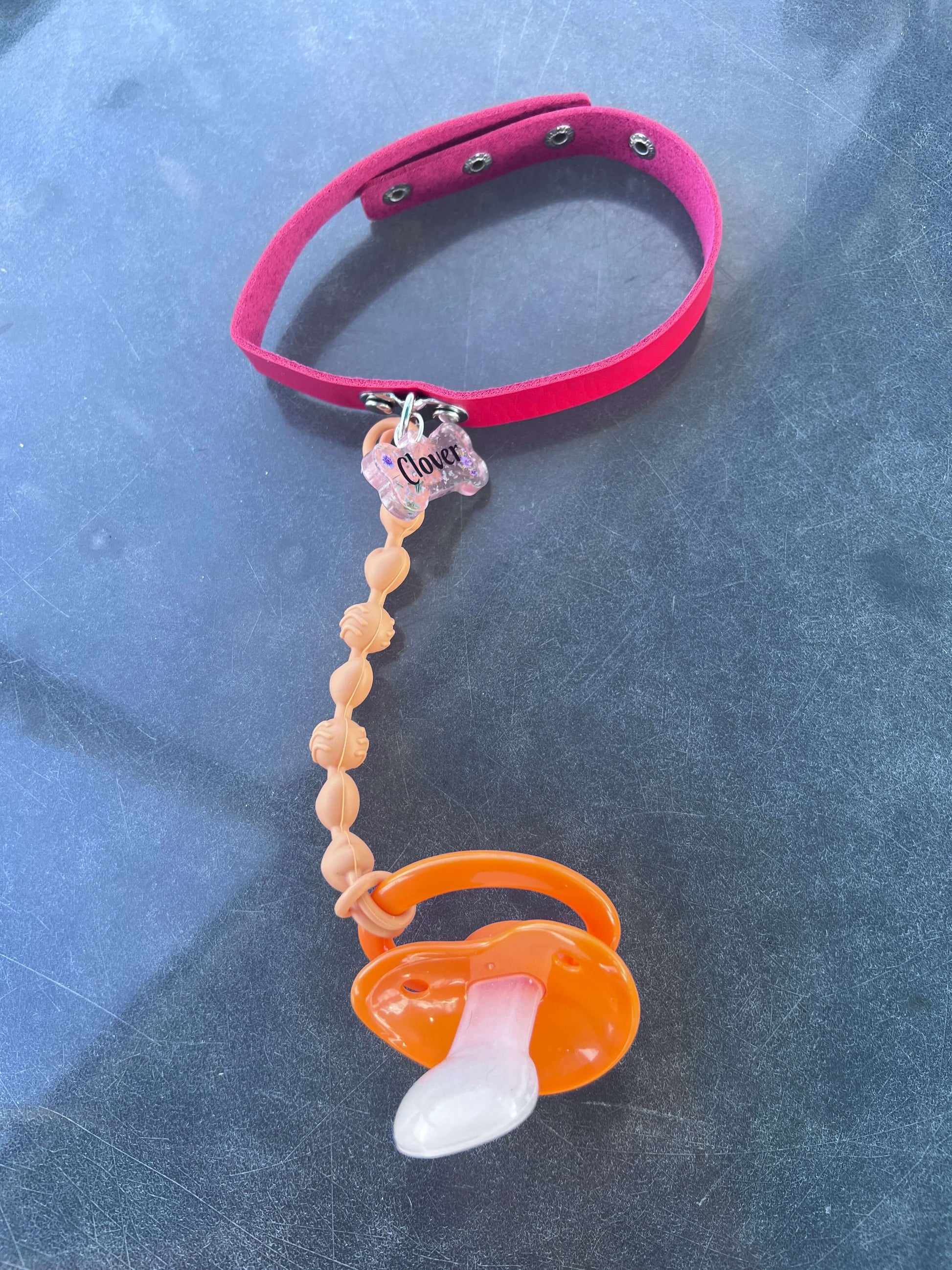 Custom adult pacifier choker featuring a leather choker, an attached adult pacifier, and a customizable resin dog tag for a personalized touch.