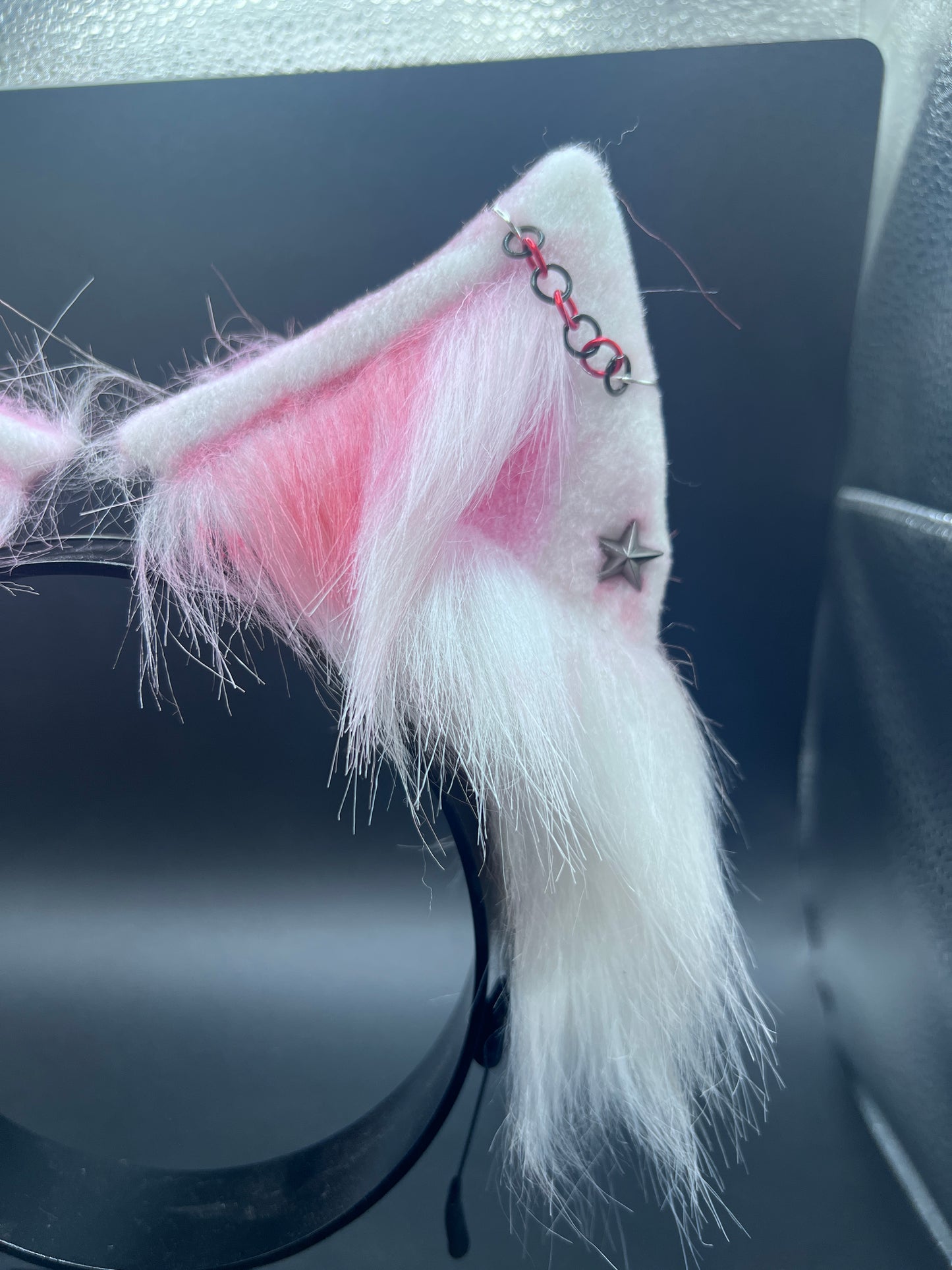 White cat ears with pink interior and decorative elements on a dark surface