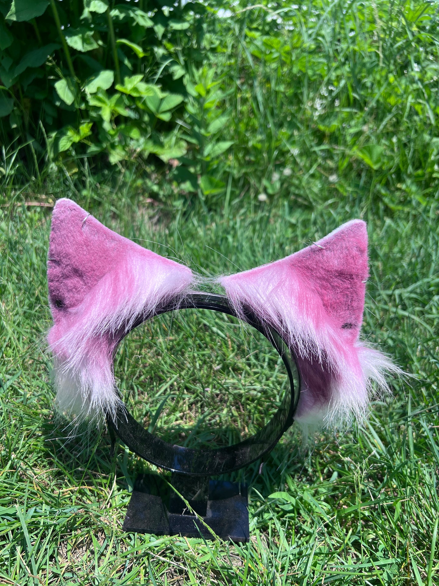 red and black cat ear headband with white bottom fur on grass