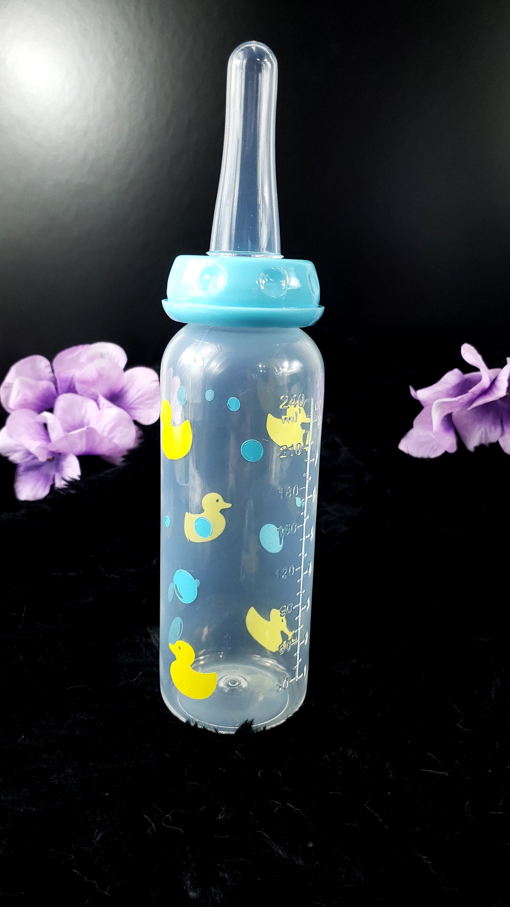 An 8oz adult baby bottle featuring a playful design with yellow ducks and blue bubbles, creating a fun and whimsical bath-time-inspired theme.
