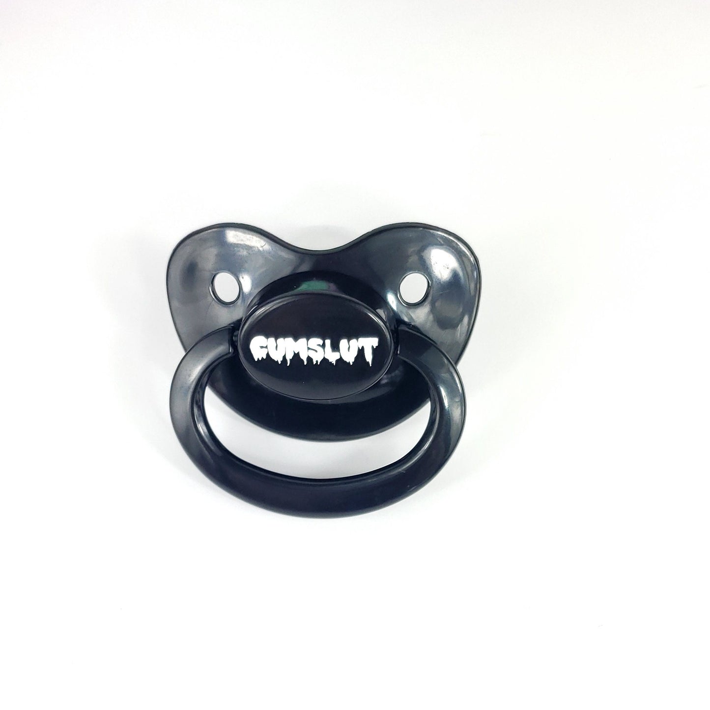 A black adult pacifier featuring the word "Cumslut" boldly displayed in the center, designed for playful and cheeky self-expression.