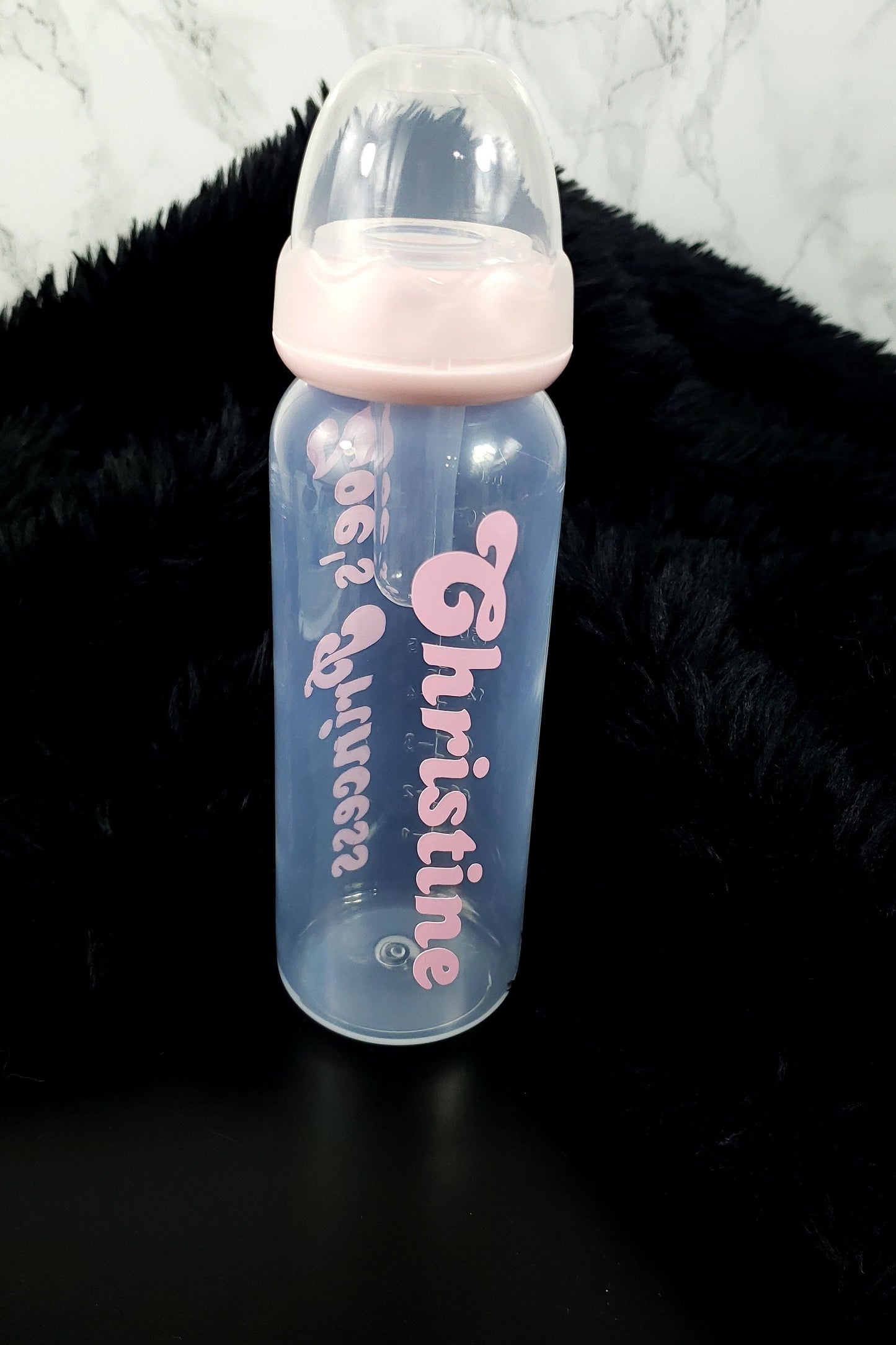 A clear baby bottle with custom vinyl personalization, featuring a long silicone nipple and personalized text on the bottle.