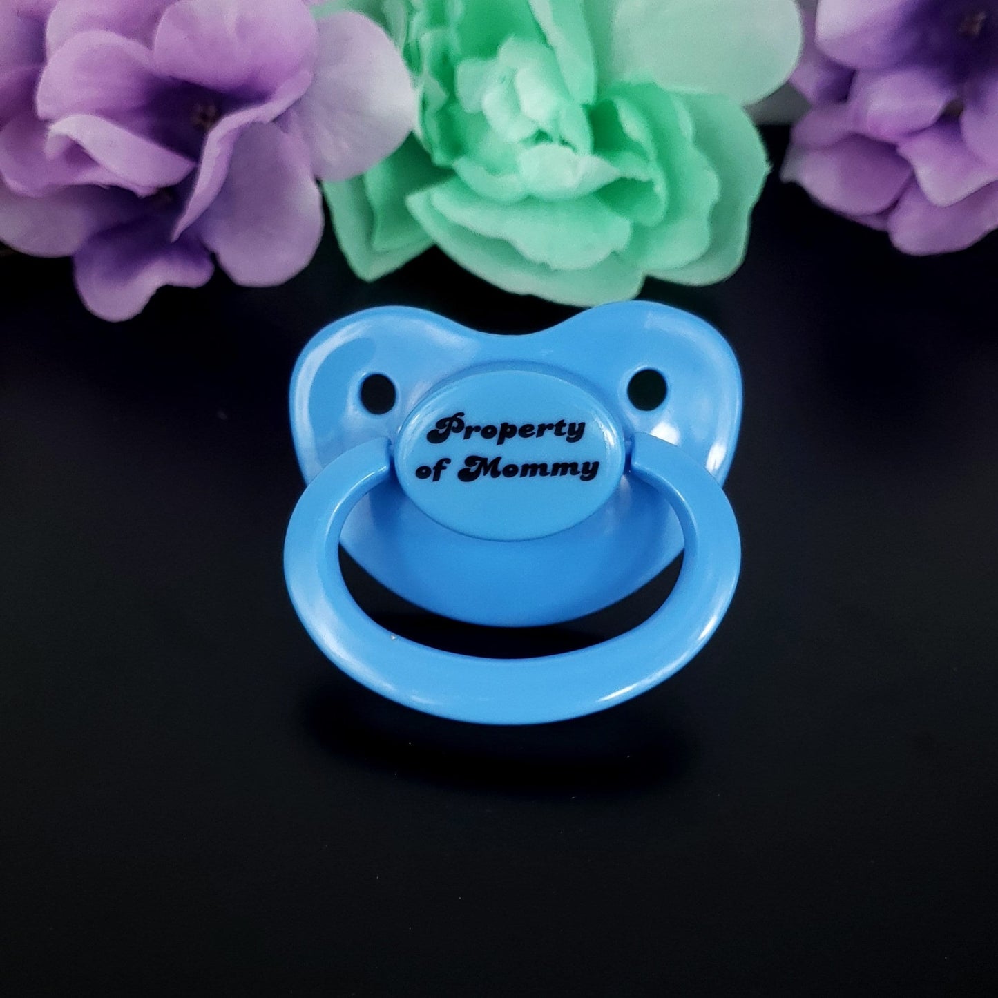 Baby blue adult pacifier with bold text saying "Property of Mommy" in the center, adding a playful and loving sentiment.
