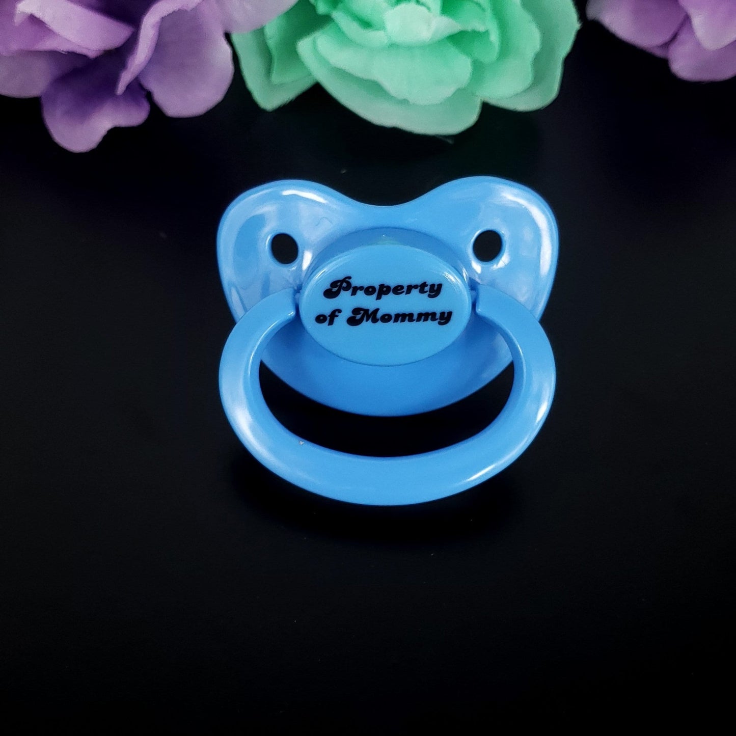 Baby blue adult pacifier with bold text saying "Property of Mommy" in the center, adding a playful and loving sentiment.