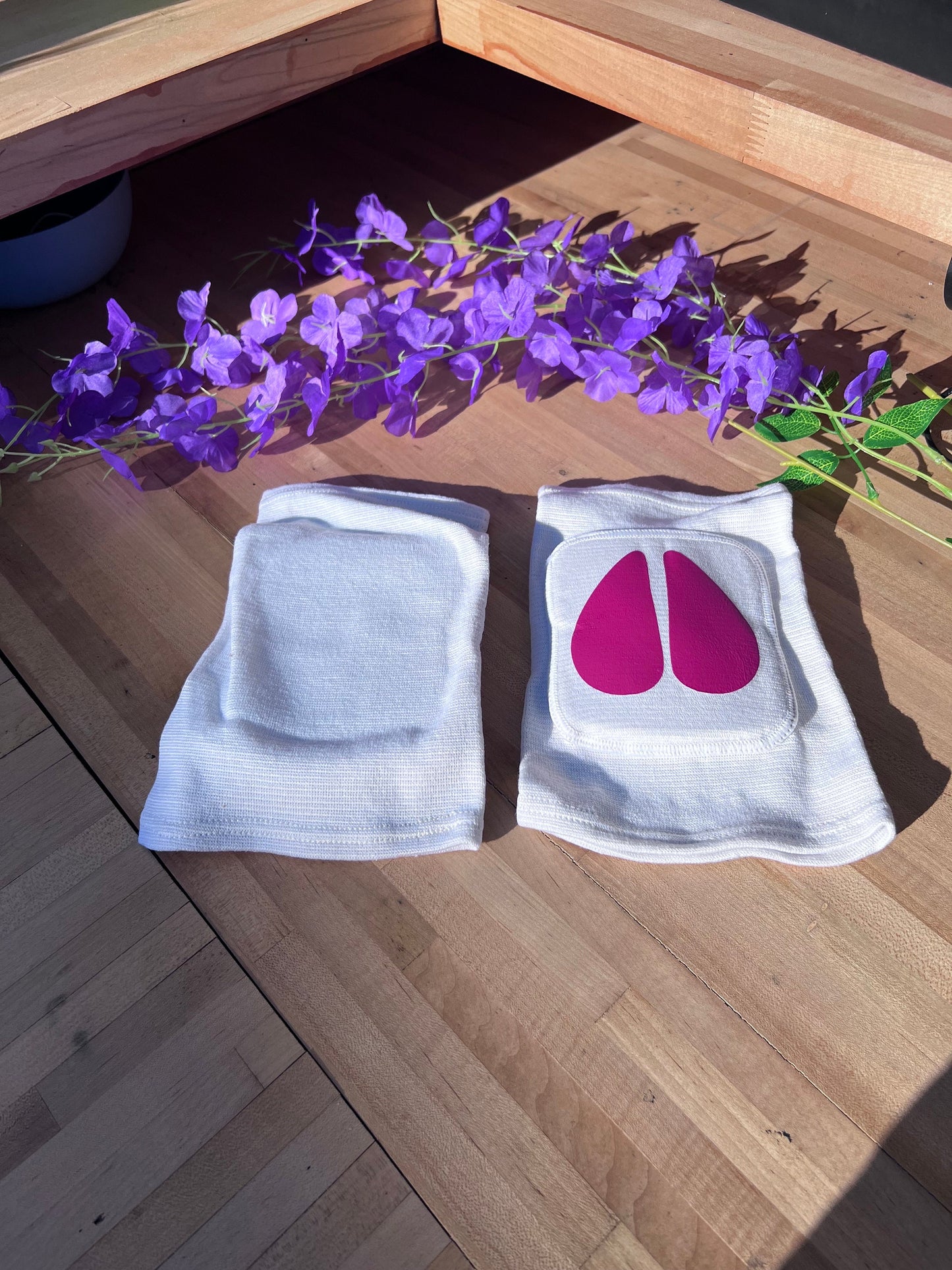 Pair of white adult knee pads with matching hot pink cow hoof centers for pet play aesthetics. One facing down to show all white back.