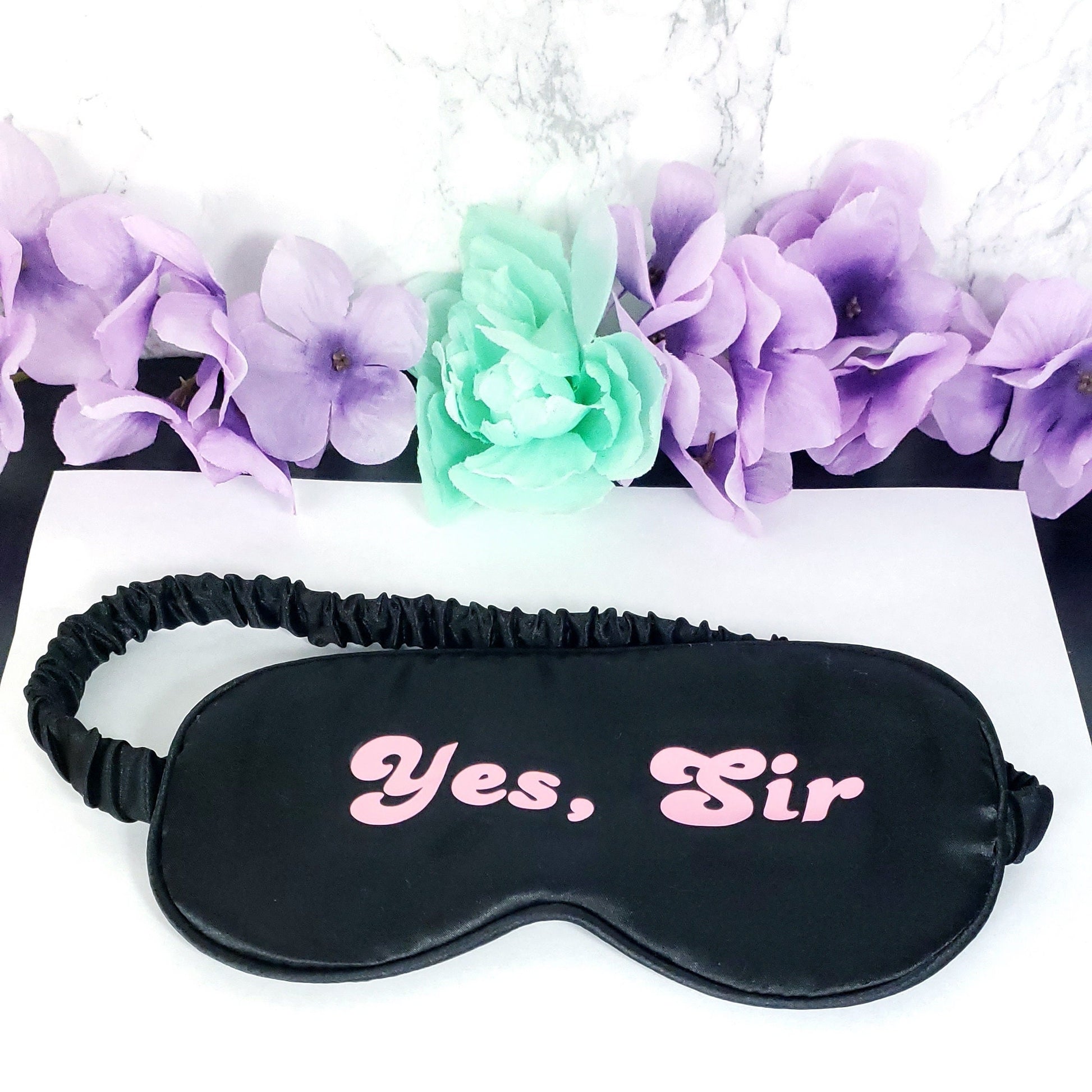 Black eye mask with the text Yes, Sir in pink on the front
