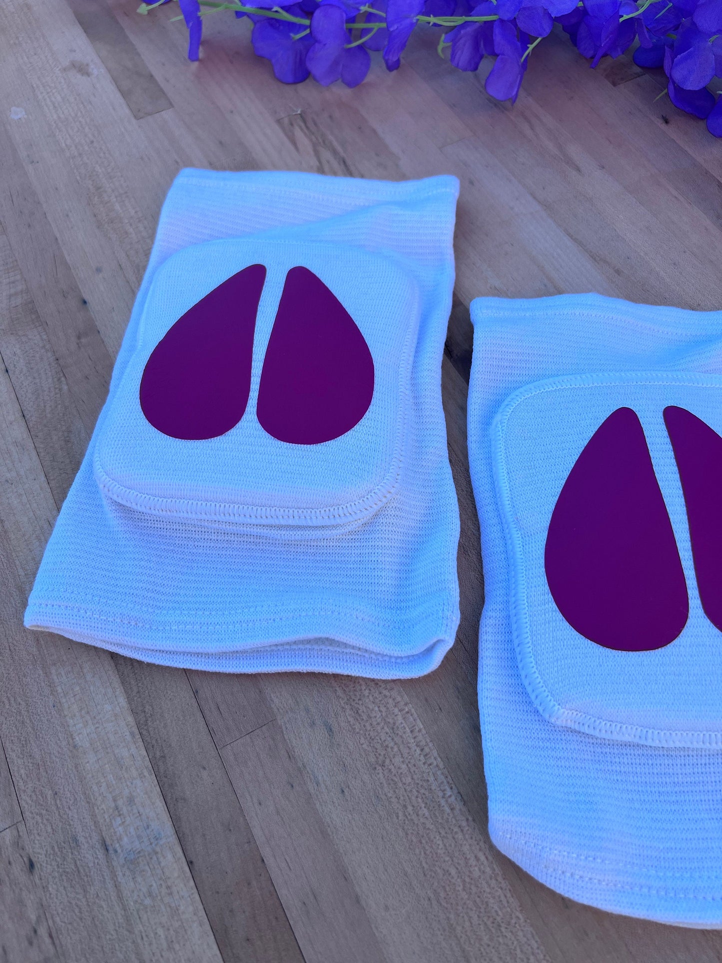 Different lighting for the same Pair of white adult knee pads with matching hot pink cow hoof centers for pet play aesthetics.