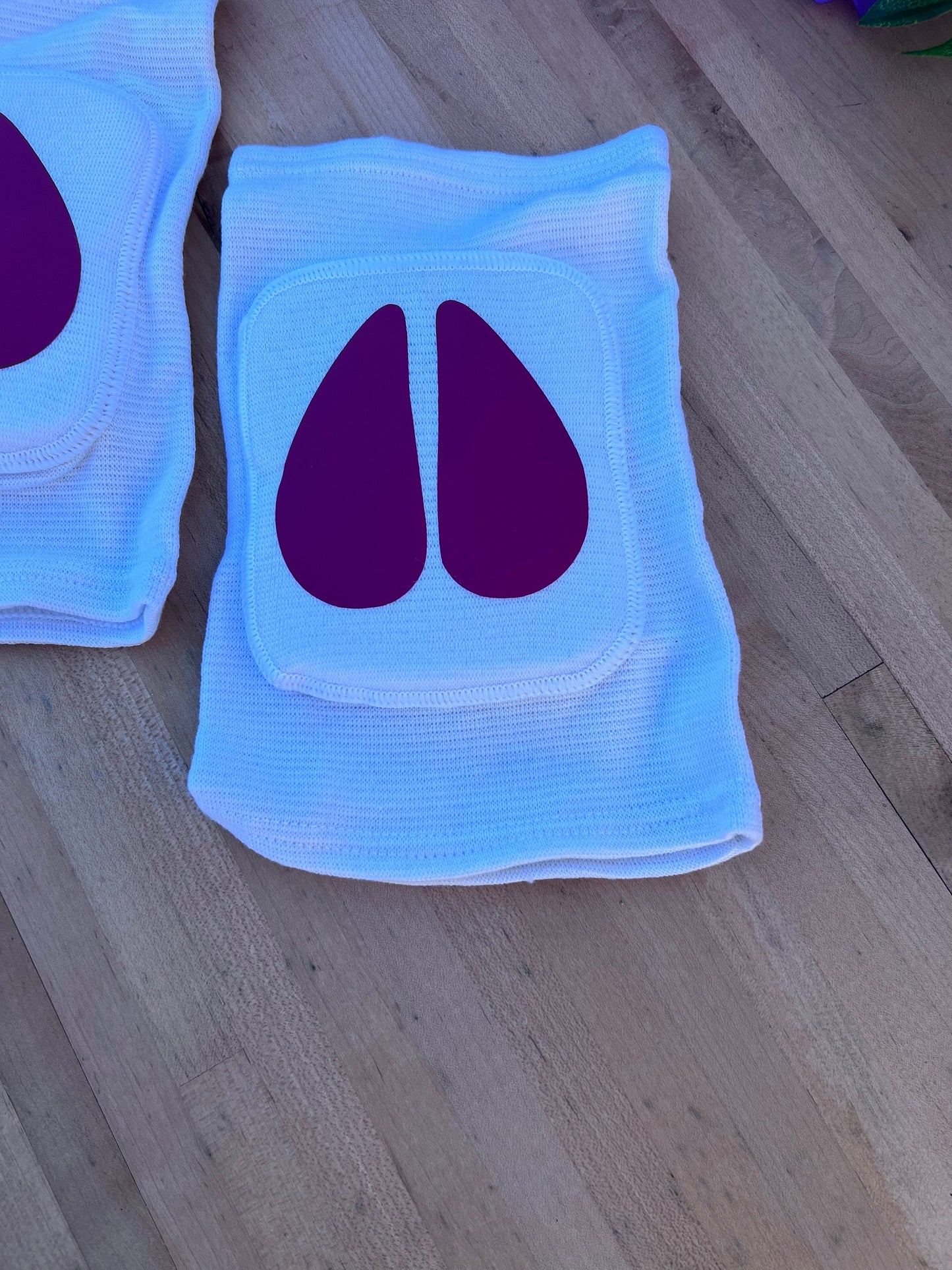 Different lighting for the same Pair of white adult knee pads with matching hot pink cow hoof centers for pet play aesthetics.