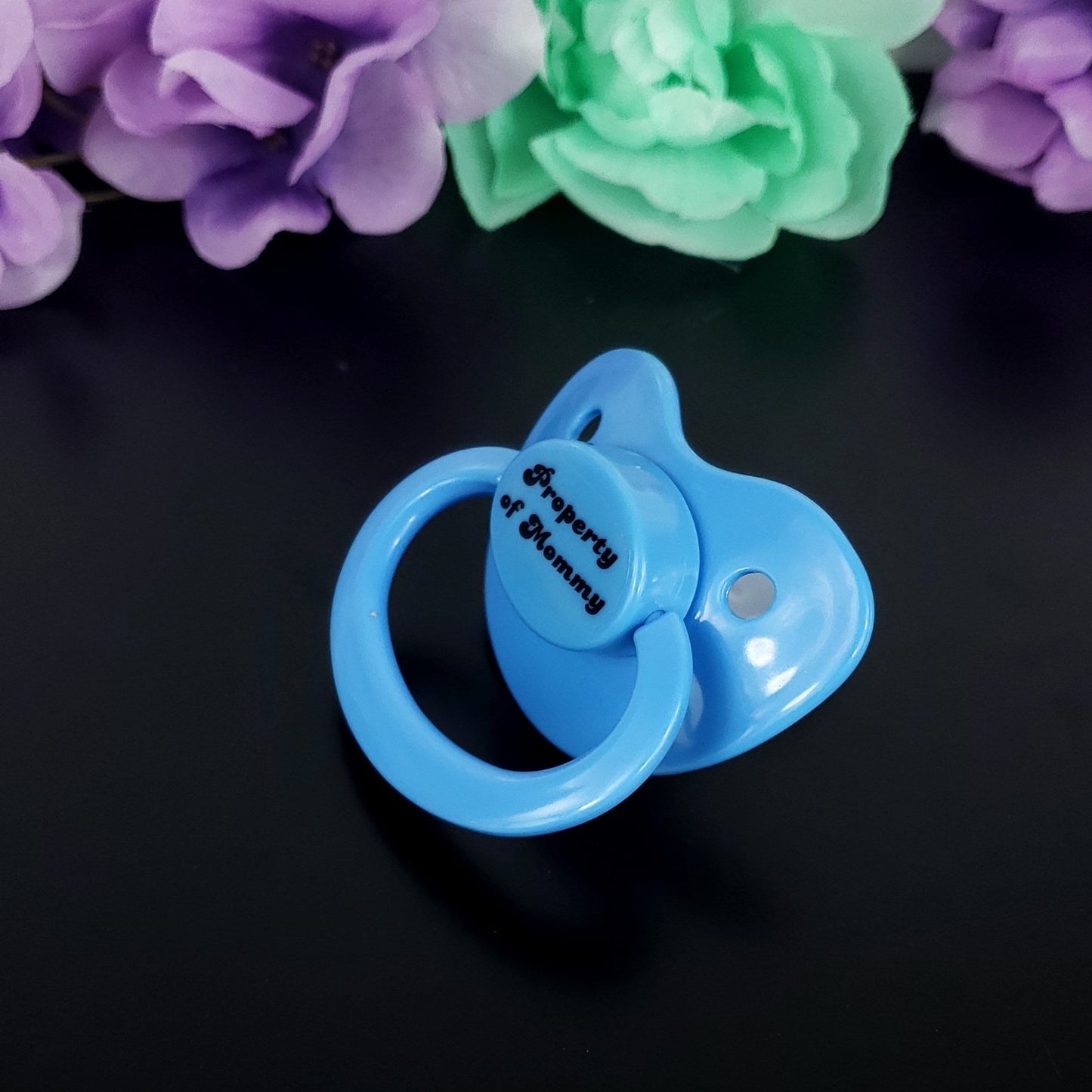 Baby blue adult pacifier with bold text saying "Property of Mommy" in the center, adding a playful and loving sentiment.