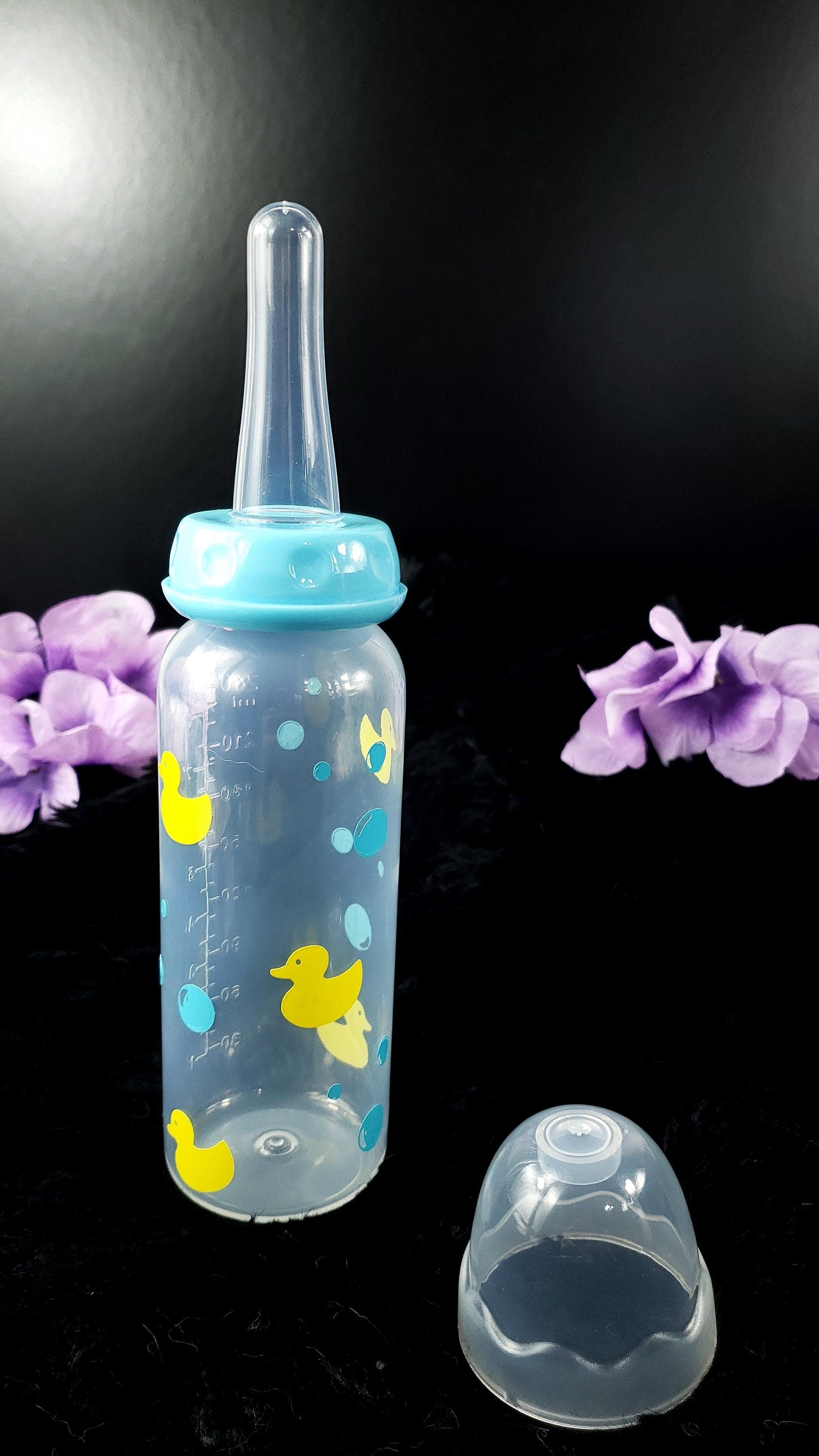 An 8oz adult baby bottle featuring a playful design with yellow ducks and blue bubbles, creating a fun and whimsical bath-time-inspired theme.
