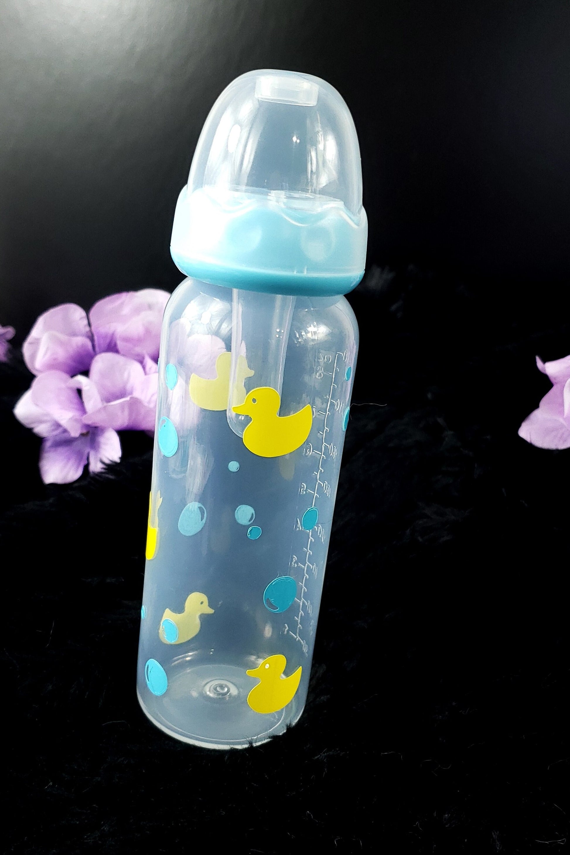 An 8oz adult baby bottle featuring a playful design with yellow ducks and blue bubbles, creating a fun and whimsical bath-time-inspired theme.