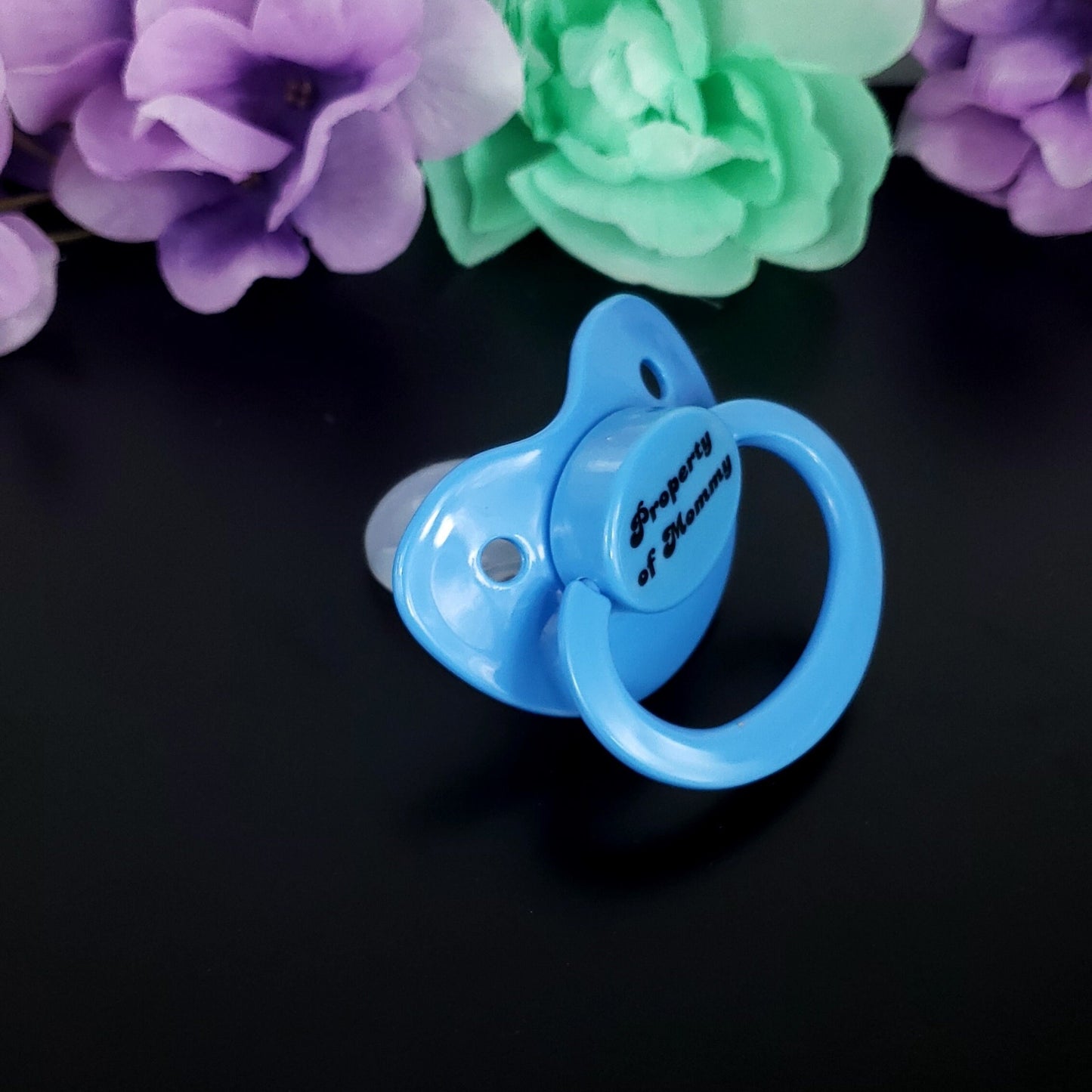 Baby blue adult pacifier with bold text saying "Property of Mommy" in the center, adding a playful and loving sentiment.
