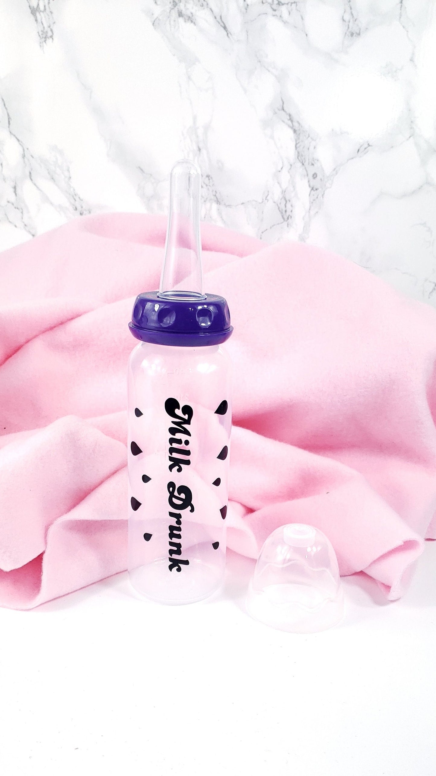 An 8oz adult baby bottle with the phrase "Milk Drunk" written in bold black text across with silhouette milk drops, offering a playful design.