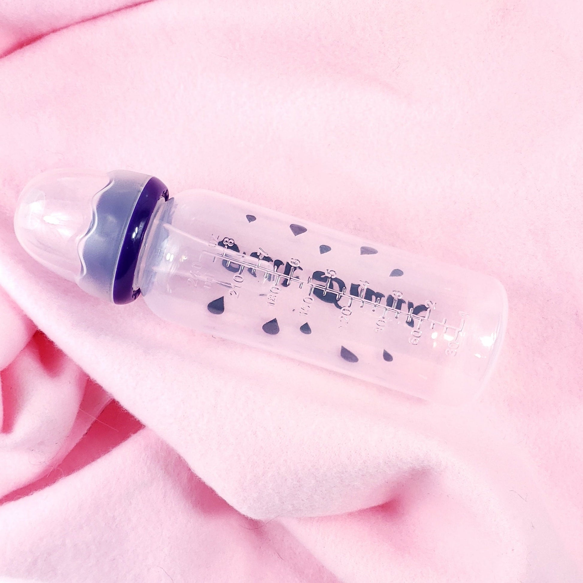 An 8oz adult baby bottle with the phrase "Milk Drunk" written in bold black text across with silhouette milk drops, offering a playful design.
