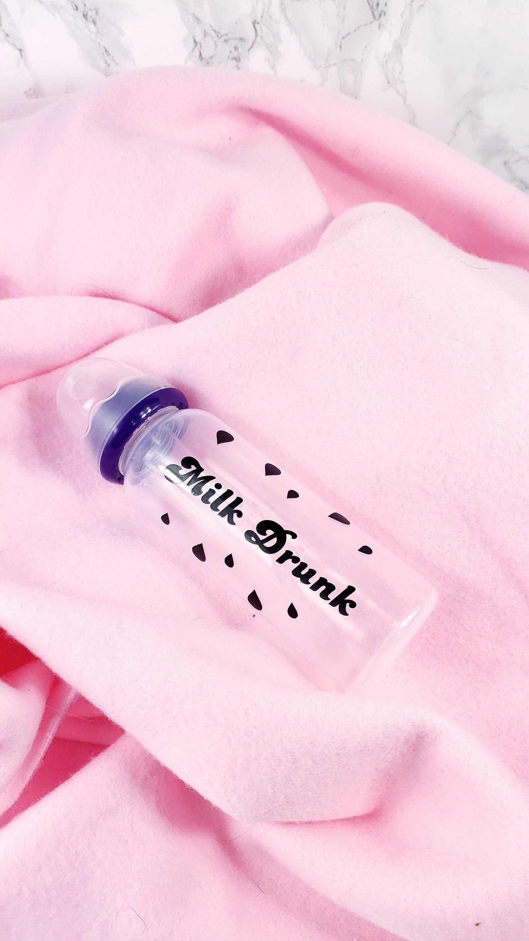 An 8oz adult baby bottle with the phrase "Milk Drunk" written in bold black text across with silhouette milk drops, offering a playful design.