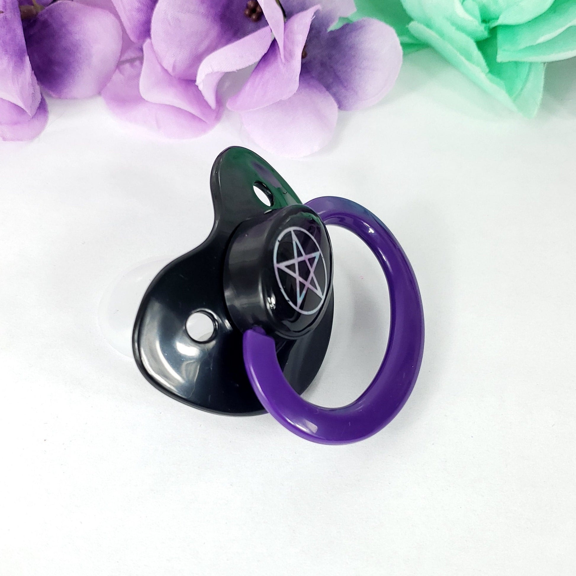 black and dark purple adult pacifier with pentagram graphic on button