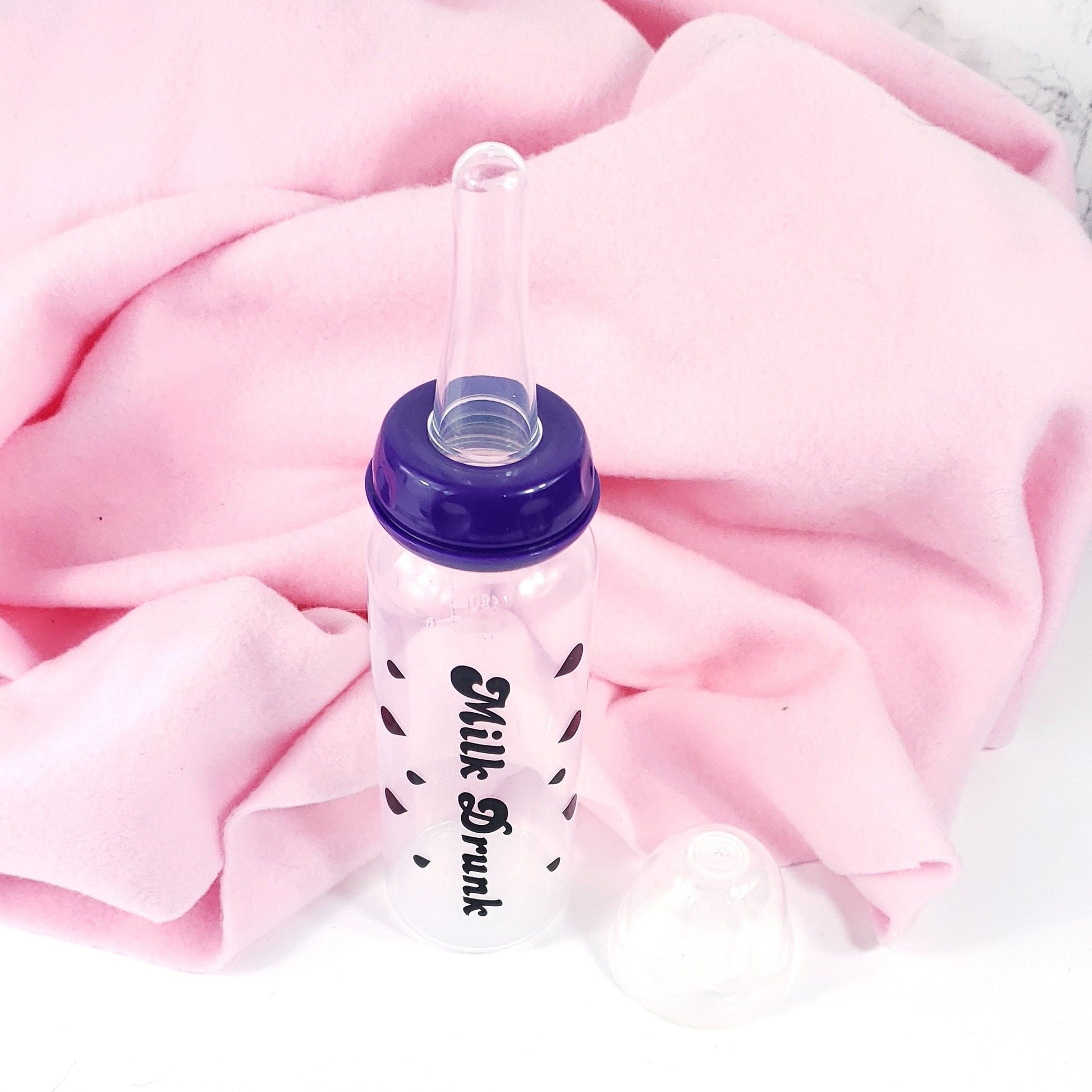 An 8oz adult baby bottle with the phrase "Milk Drunk" written in bold black text across with silhouette milk drops, offering a playful design.