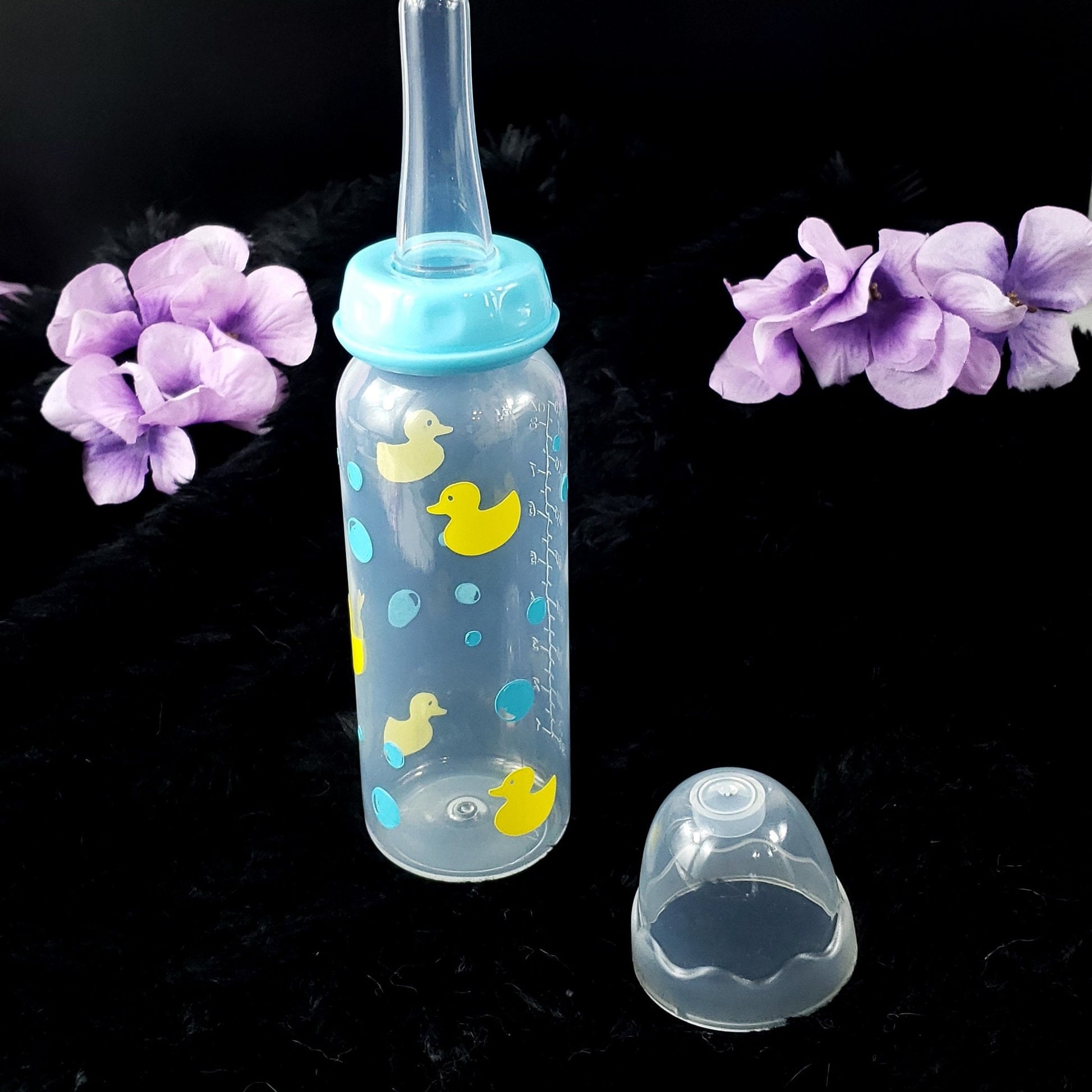 An 8oz adult baby bottle featuring a playful design with yellow ducks and blue bubbles, creating a fun and whimsical bath-time-inspired theme.