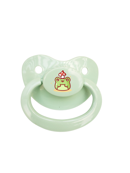 mint green adult pacifier featuring a kawaii frog with a mushroom on it's head