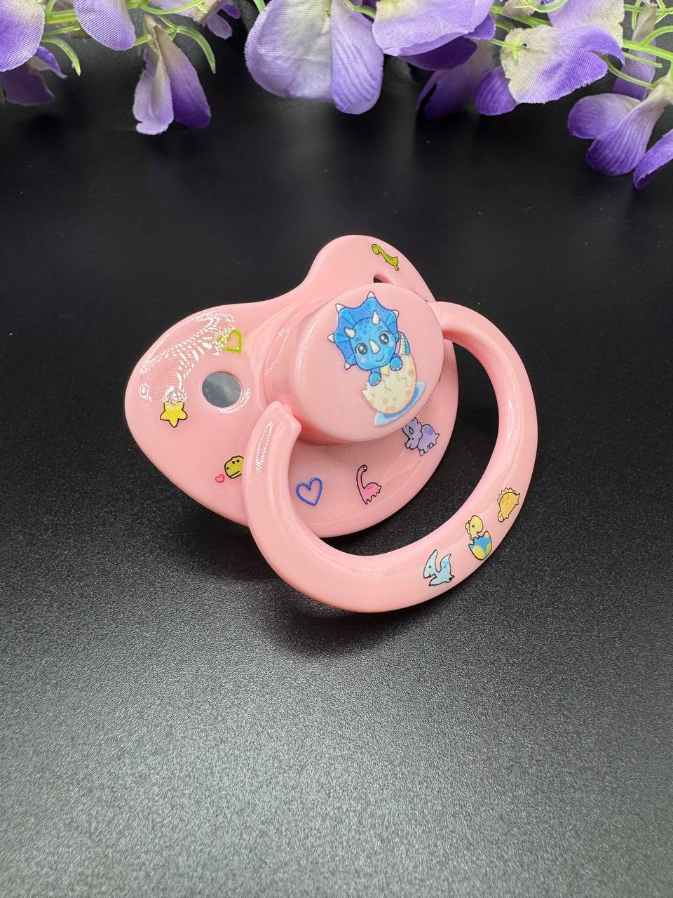 baby pink little space adult pacifier with glow in the dinosaurs design