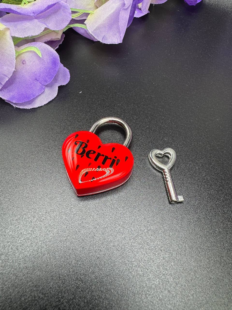 Red heart-shaped lock with a key with text Berri and seed design to mimic strawberries