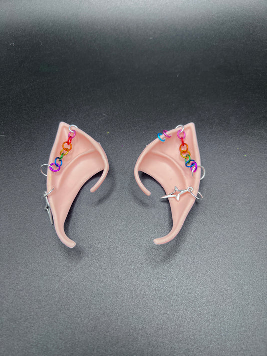 fantasy fairy elf ears with rainbow chain going across and star earrings. Left ear has 2 extra loop piercings in pink and blue