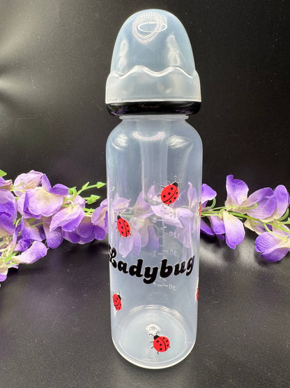 Clear ABDL bottle with ladybug design on a black background with purple flowers