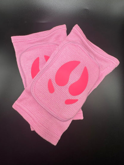 A pair of light pink ribbed knit knee pads with a darker pink pig hoof printed on the front