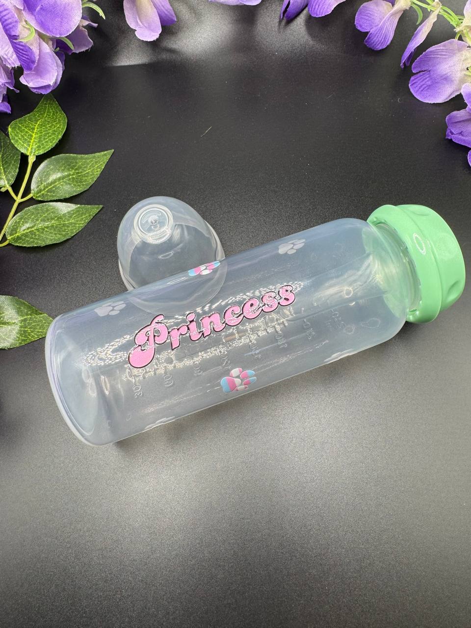 ABDL 8 oz bottle with the text Princess in pink bubbly text and trans pride paw prints surrounding text