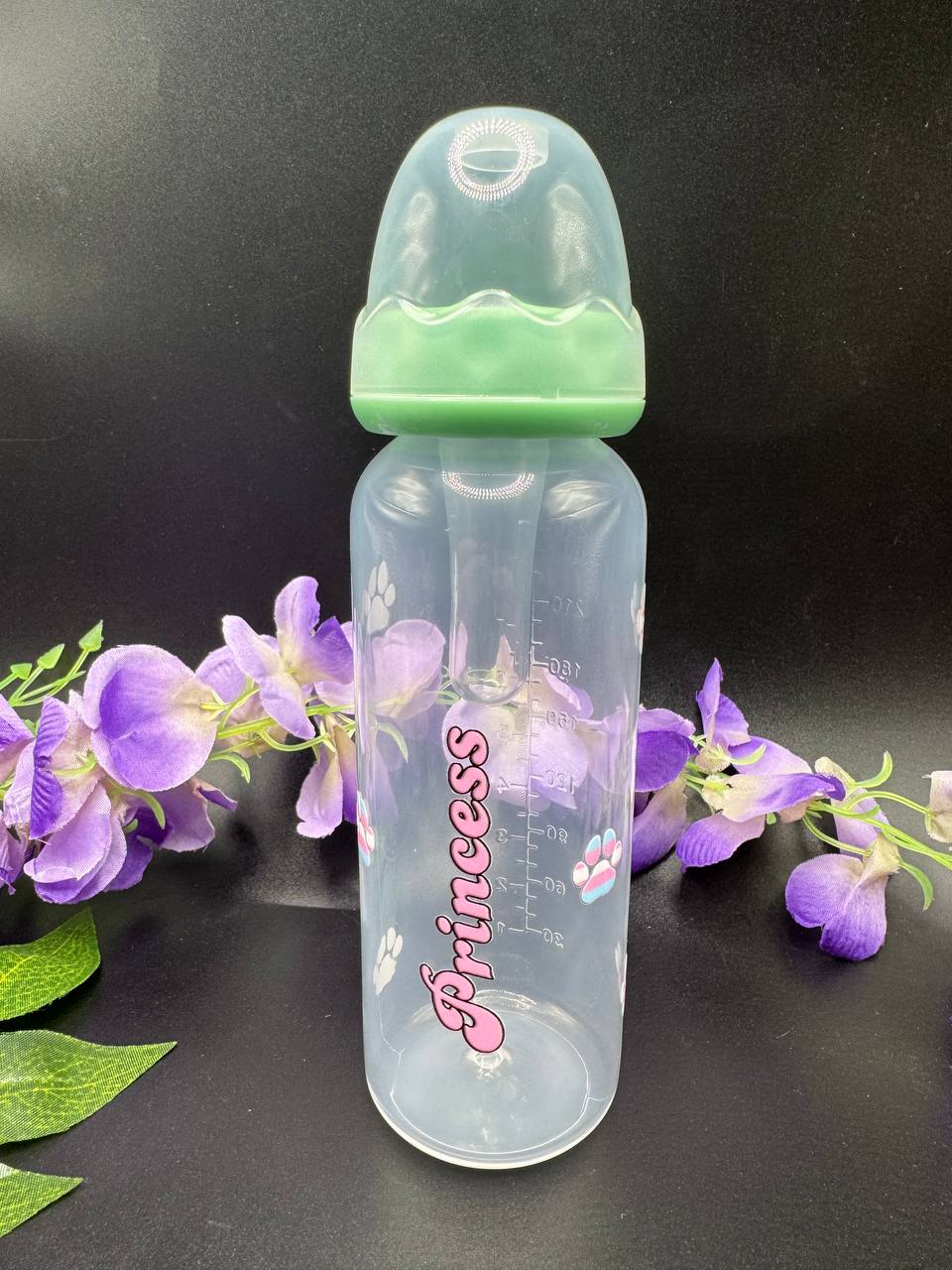 Clear adult baby bottle with green cap and 'Princess' text with trans pride paw prints