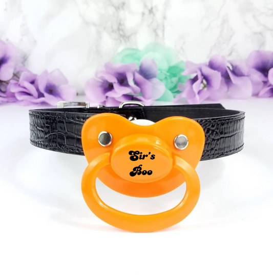halloween themed adult pacifier gag for ABDL. Orange pacifier with black straps and text that reads Sir's Boo