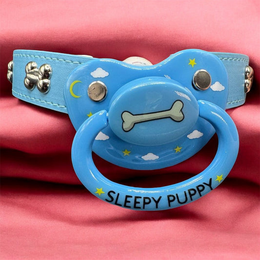 Blue dog bone collar gag with a pacifier attachment on a pink background